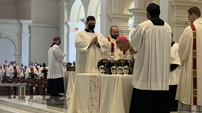 Bishop Luis Rafael Zarama blesses the sacred Chrism as brother priests and deacons look on.