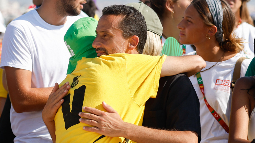 People share the sign of peace while Pope Francis celebrates Mass for World Youth Day at Tejo Park in Lisbon, Portugal, Aug. 6, 2023. (CNS photo/Lola Gomez)