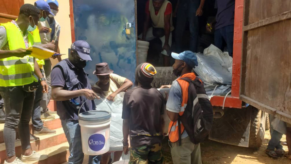 Earthquake victims receive hygiene kits and tarps from Catholic Relief Service workers in Les Cayes, Haiti, Aug. 24, 2021. CRS staffers are operating under tarps at a parking lot near their operations center in Les Cayes following damage to their offices. (CNS photo/Godchild Regis, CRS)